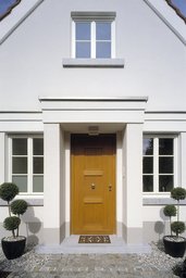 Symmetrischer Hauseingang mit profilierter Portalrahmung, Holzhaustür und flankierenden Sprossenfenstern