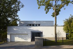 Straßenseitige Fassade des kubischen Wohnhauses mit Doppelgarage und Eingangsnische