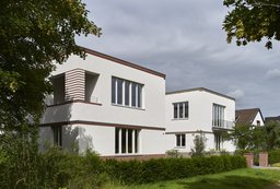 Fassaden beider kubischen Einfamilienhäuser mit hellen Putzfassaden und Klinkerbändern