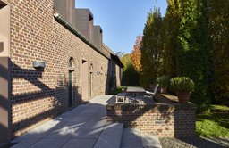 Gepflasterte Gartenterrasse an historischer Backsteinfassade mit modernen Zinkgauben