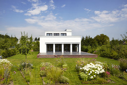Gartenansicht des kubischen Baukörpers mit Klinkersockel, Terrasse und Staudenbeeten