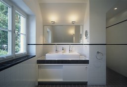 Badezimmer mit breitem Doppelwaschtisch, schwarz-weißer Fliesengestaltung und großem Wandspiegel