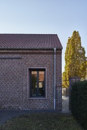 Fassadendetail aus historischem Ziegelmauerwerk mit modernem Einzelfenster und Dachkante