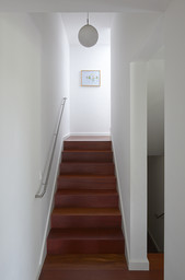 Geradlinige Holztreppe mit minimalistischem Edelstahlhandlauf und runder Hängeleuchte