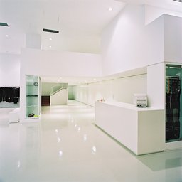 Monolithischer weißer Verkaufstresen mit Glasvitrine und Treppenaufgang zur Galerie