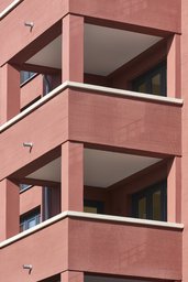 Detailansicht der gestapelten Balkone mit strukturierter roter Putzfassade