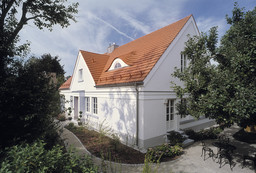 Außenansicht des Wohnhauses mit Satteldach, markanter Fledermausgaube und Kiesterrasse