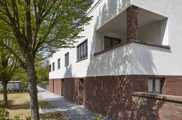 Perspektivische Fassadenansicht mit Backsteinsockel, Eckloggia und gepflastertem Zuweg