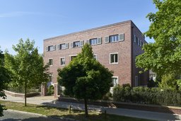 Perspektivische Straßenansicht der dreigeschossigen Klinkerfassade mit Fensterläden im Obergeschoss