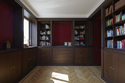 Bibliothekszimmer mit dunklem Holzeinbau, roter Akzentwand und feinem Fischgrätparkett