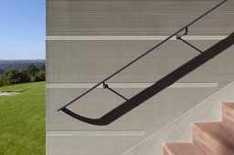 Außentreppe mit filigranem Handlauf an horizontal gekämmter Sockelfassade
