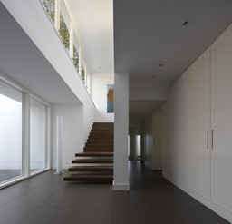 Großzügiges Foyer mit schwebender Holztreppe, Einbauschränken und hoher Fensterfront