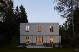 Symmetrische Gartenfassade in der Abenddämmerung mit warm erleuchteten Fenstern
