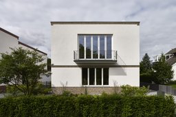 Symmetrische Fassadenansicht des kubischen Wohnhauses mit Balkon und Klinkergesims
