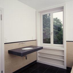 Badezimmer mit freitragendem Naturstein-Waschtisch und Fensterlaibung mit integrierten Regalen