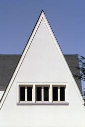 Detailansicht des steilen weißen Spitzgiebels mit dreiteiligem Fensterband und Schieferdach