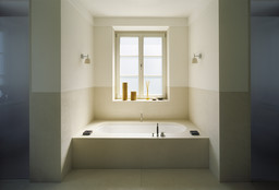 Eingelassene Badewanne in symmetrischer Nische unter dem Fenster mit Wandleuchten