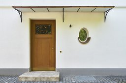 Hauseingang mit filigranem Stahlvordach, Eichentür, Natursteinstufe und ovalem Fenster