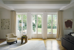 Lichtdurchfluteter Wohnraum mit Fischgrätparkett und bodentiefen Fenstertüren zum Garten