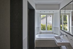 Badezimmer mit eingelassener Badewanne vor dem Fenster und modernem Waschtisch