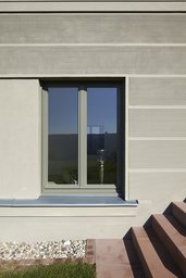 Sockelfassade mit horizontal gekämmtem Putz, zweiflügeligem Holzfenster und Sandsteintreppe