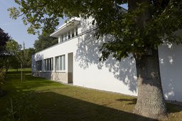 Gartenfassade mit Natursteinsockel, Fensterband, Staffelgeschoss und altem Baumbestand