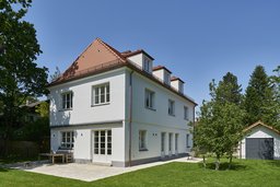 Perspektivische Gartenansicht des Einfamilienhauses mit Terrasse, Walmdach mit Biberschwanzdeckung und drei Gauben