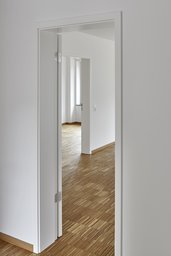 Blickachse durch weiße Türöffnungen in helle Wohnräume mit Stäbchenparkett