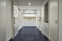 Klinischer Funktionsflur mit blauem Bodenbelag, Einbauschränken und integrierter Waschstation