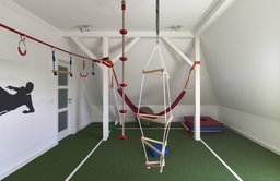 Ausgebautes Dachgeschoss als Spiel- und Bewegungsraum mit weiß gestrichenem Holztragwerk
