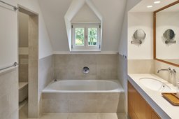 Helles Dachgeschossbad mit eingepasster Badewanne unter dem Gaubenfenster