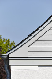Fassadendetail am Dachrand mit Schieferdeckung, horizontaler Holzverschalung und Zinkrinne