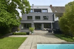 Gartenfassade mit dunkelgrauem Besenstrichputz, Zink-Stehfalzdach, Terrasse und Pool