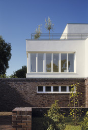 Fassadendetail mit dunklem Klinkermauerwerk, weißem Obergeschoss und Dachterrasse