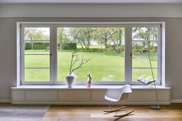 Großflächiges Panoramafenster mit Fenstersitzbank und weitem Gartenblick