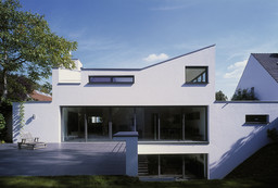 Gartenansicht mit Terrasse, bodentiefer Verglasung und asymmetrischer Dachlinie
