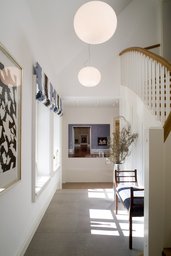 Lichtdurchflutetes Foyer mit Treppenaufgang, Kugelpendelleuchten und großformatigen Bodenfliesen