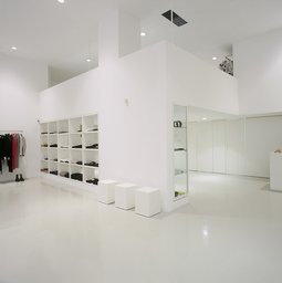 Minimalistischer Verkaufsraum mit integrierter Regalwand, Glasvitrine und weißem Galerieeinbau