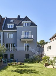 Rückwärtige Gartenfassade mit erhöhter Terrasse, Außentreppe und privater Grünfläche