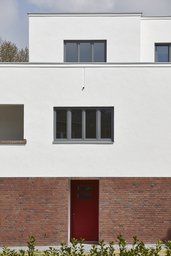 Fassadenausschnitt der Straßenfront mit roter Eingangstür, Loggia und Staffelgeschoss