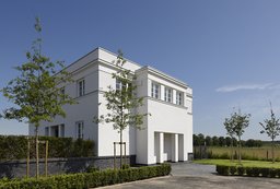 Perspektivische Außenansicht der weißen Villa mit Eingangsrisalit und Klinkersockel