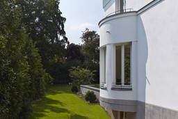 Halbrunder Erker an der weißen Putzfassade mit Blick in den Garten
