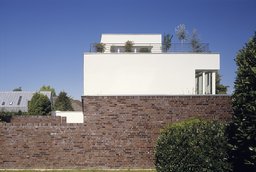 Dunkler Klinkersockel mit weiß verputztem Obergeschoss und bepflanzter Dachterrasse