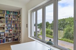 Arbeitszimmer mit raumhohem Bibliotheksregal und großem Fensterband mit Rheinblick