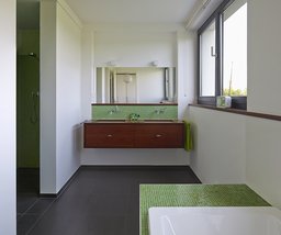 Helles Badezimmer mit grünem Glasmosaik, hängendem Doppelwaschtisch und Fliesenboden