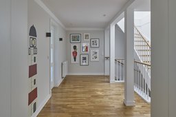 Helle Diele mit Parkettboden, weißem Stützentragwerk und offenem Treppenaufgang