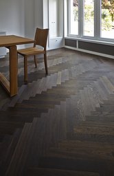 Dunkler Fischgrät-Parkettboden im Essbereich mit Holzmöbeln und heller Fensterfront