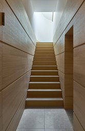 Geradläufiger Holztreppenaufgang mit horizontal gegliederter Wandverkleidung und zenitalem Oberlicht
