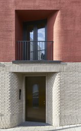Eingezogener Hauseingang im hellen Klinkersockel mit französischem Balkon darüber