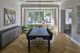 Esszimmer mit Fischgrätparkett, langer Holztafel und Fensterfront
